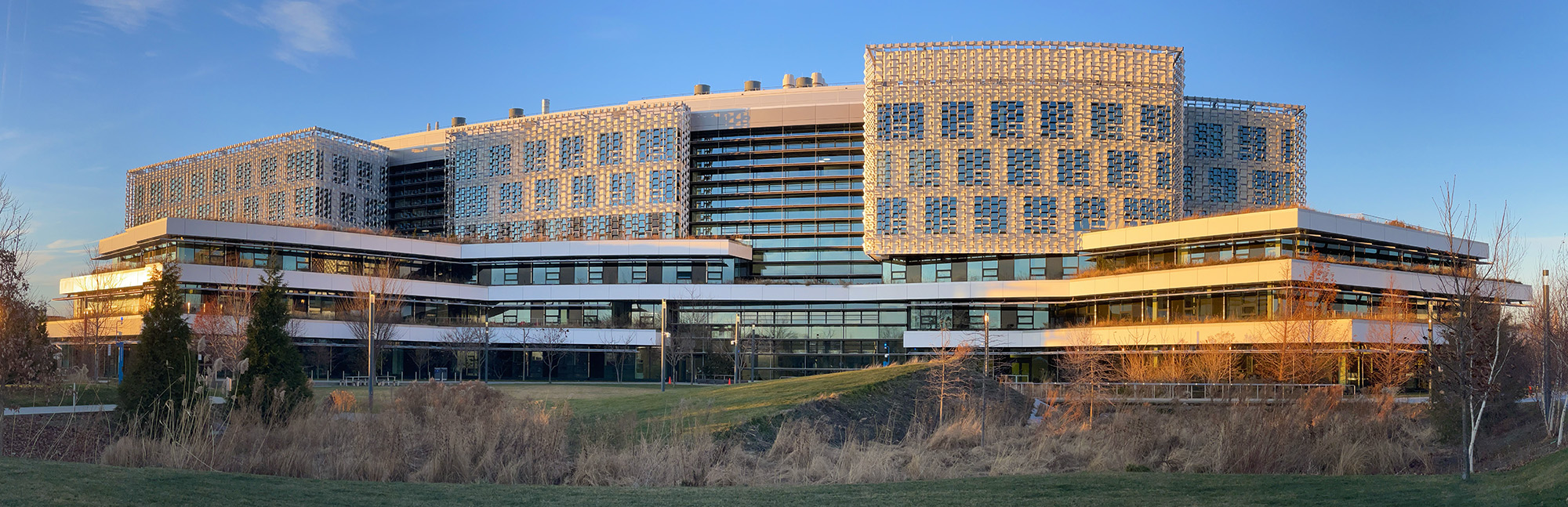 A landscape picture of the Harvard Science Engineering Complex with a sunset from the left and blue skies.